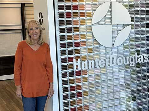The owner standing next to a wall of color swatches.